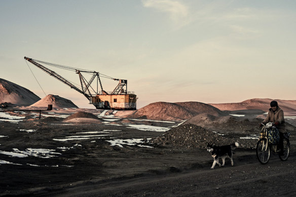 A woman cycles past with her dog as excavators mine rare earth minerals in the Zhytomyr region of Ukraine in February. 