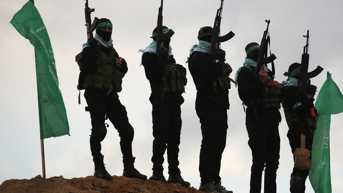 Hamas terrorists in black with green flags, weapons