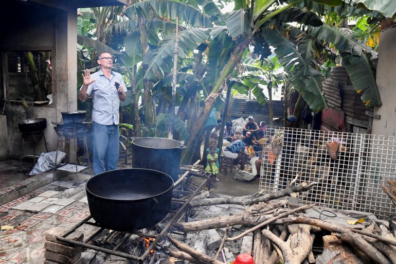 Jose Daniel Ferrer speaks next to a large castiron pot where food is cooking outdoors in Santiago de Cuba.