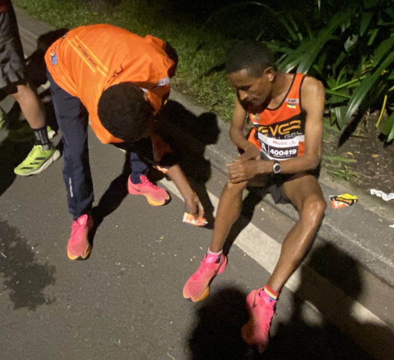 Ethiopian runner Miko applies balm to teammate Keress's leg before a race in Vietnam [Danh Nguyen]