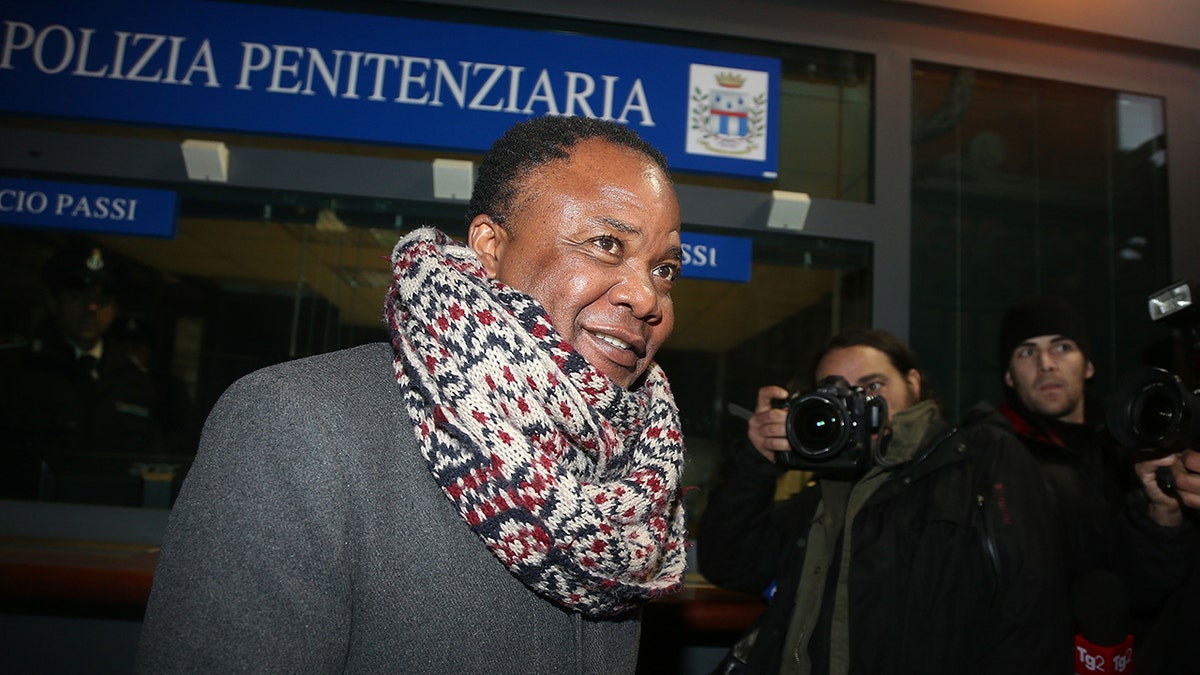 Patrick Lumumba wearing a scarf and a grey sweater smiling.