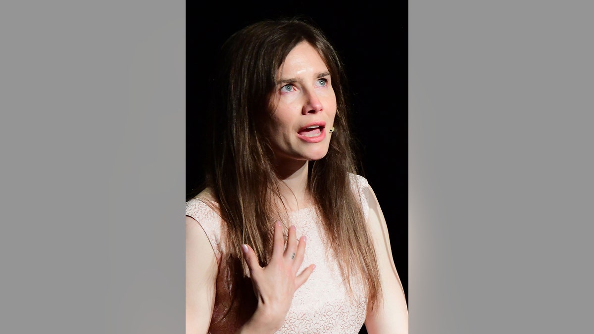 Amanda Knox speaking on stage wearing a peach blouse.