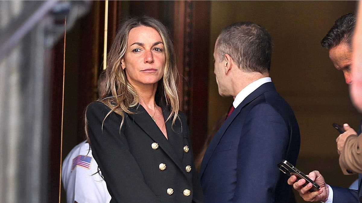 Karen Read stands outside courthouse, wearing a blazer and holding her bag