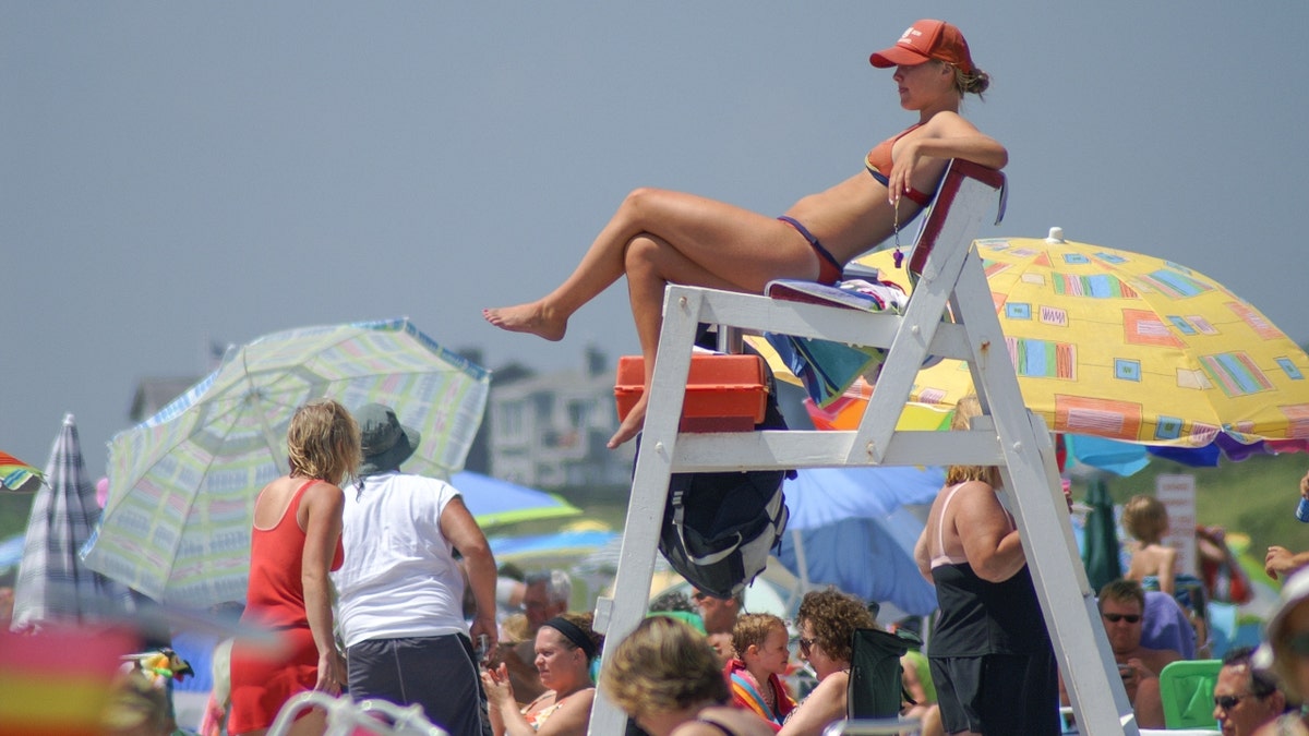 Female lifeguard in a two piece bathing suit on duty at Roger Williams State beach also known as Sand Hill Cove on a sunny summer day