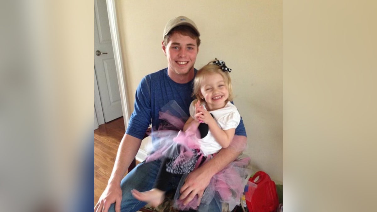 Jacob Couch smiles holding a young girl on his lap