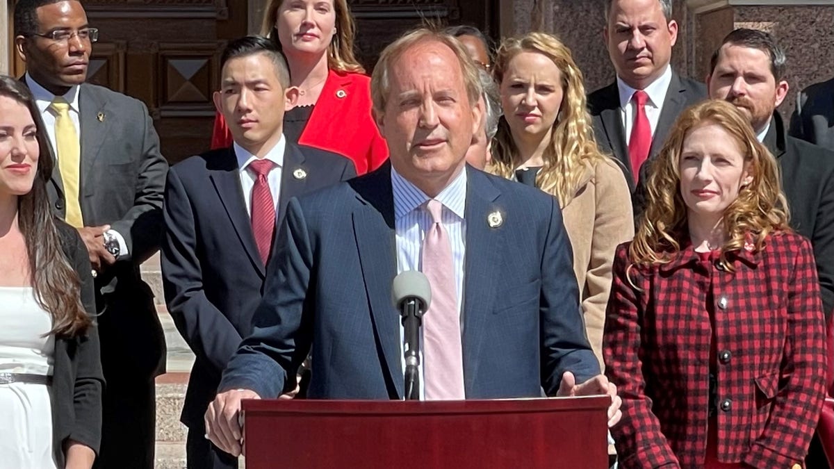 Paxton at lectern with people behind him