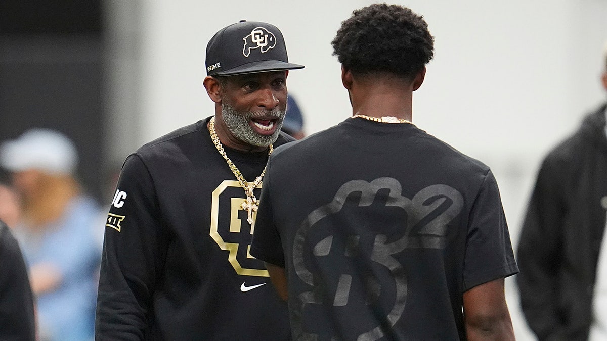 Colorado head coach Deion Sanders, left, talks with his son, quarterback Shedeur Sanders, before passing drills at Colorado's NFL football pro day Friday, April 4, 2025, in Boulder, Colo. 
