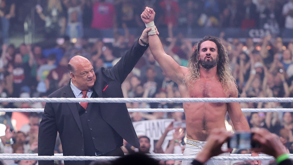 Paul Heyman raises Seth Rollins' hand