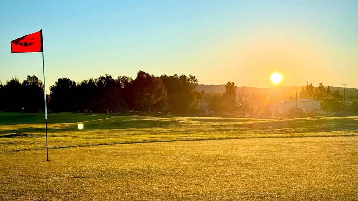 A sunset over the putting green at Skylinks Golf Course in Concord, California, with a red flag blowing in the wind
