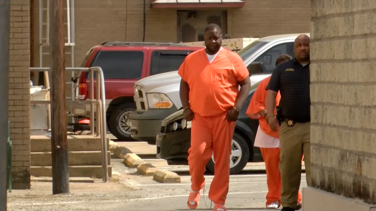Albert Creath wearing an orange jumpsuit while being taken into jail.