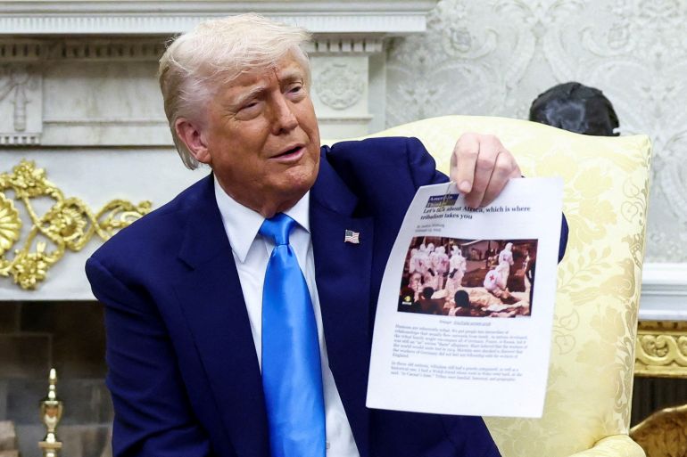U.S. President Donald Trump shows a copy of an article that he said its about white South Africans who had been killed, in the Oval Office of the White House in Washington, D.C., U.S., May 21, 2025. REUTERS/Kevin Lamarque TPX IMAGES OF THE DAY