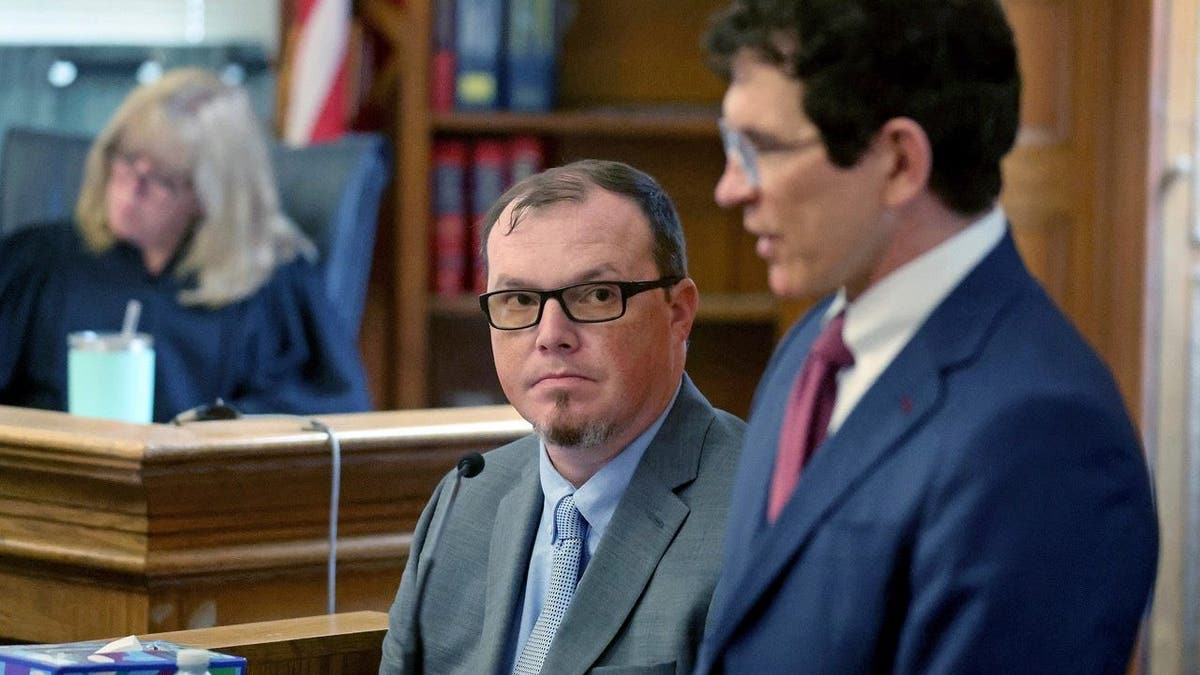Robert Alessi stands next to a seated Shanon Burgess during the latter's testimony in court
