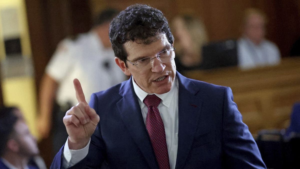 Defense attorney Robert Alessi raises his finger while wearing a blue suit and red tie