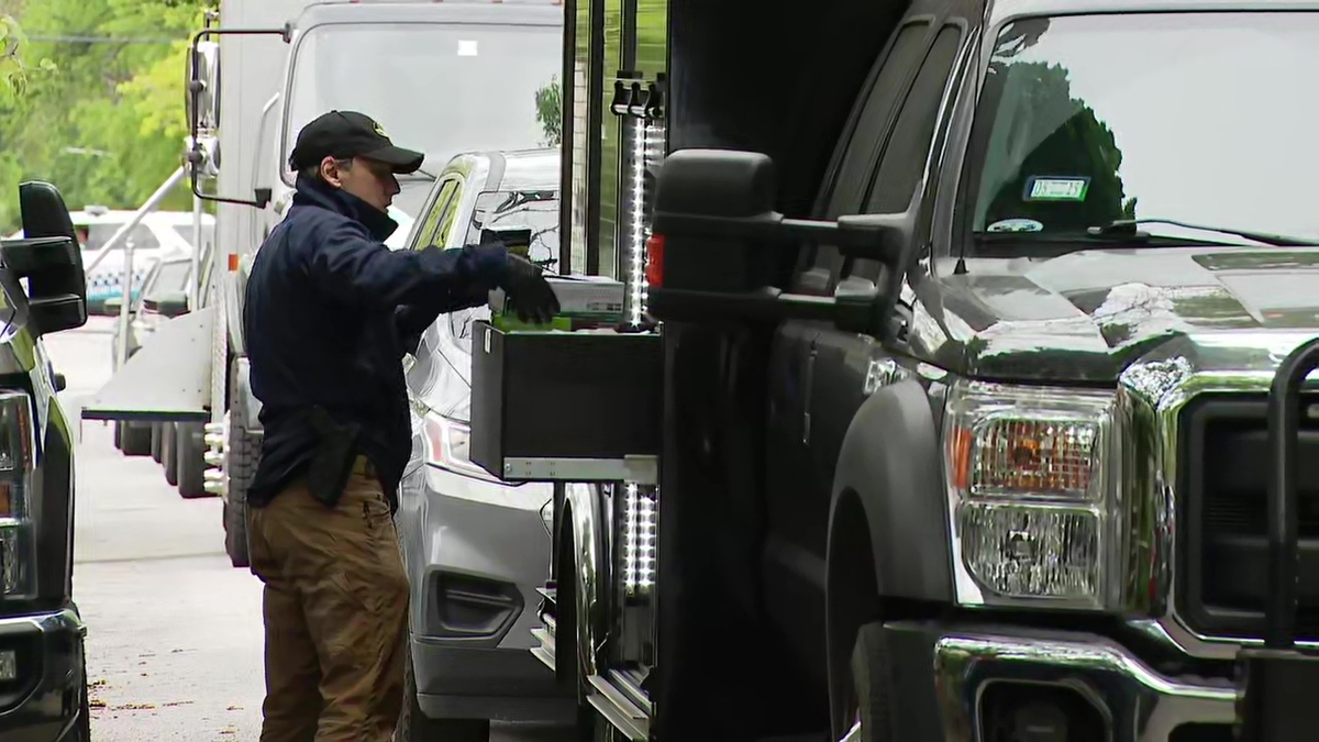 An investigator reaches into a box on the side of a government vehicle