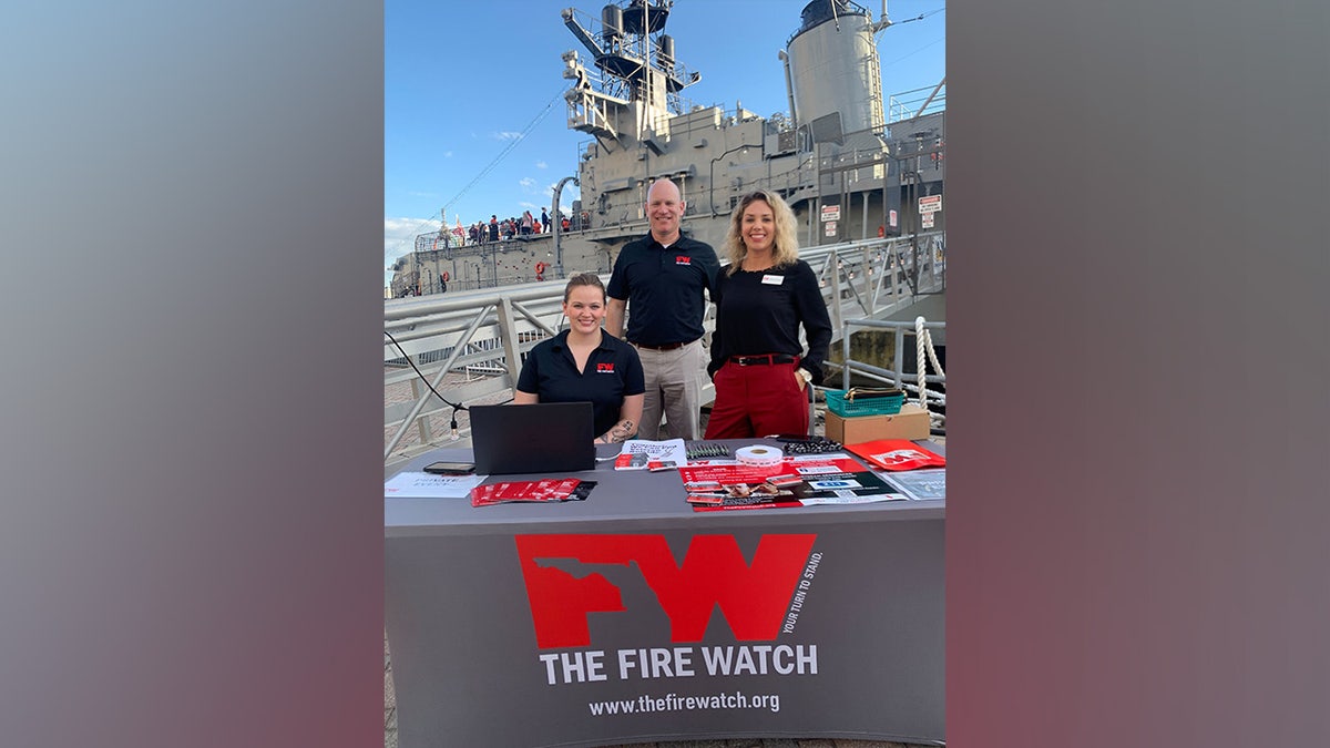 The Fire Watch volunteers in front of a table advertising the nonprofit's work