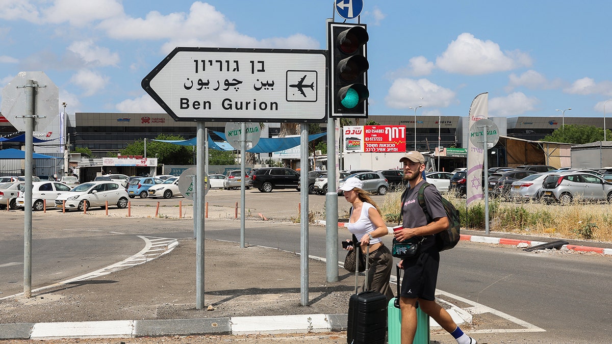 Travelers walk toward Ben Gurion Airport after main road entrances to the facility were closed by Israeli police in response to a missile launched from Yemen on May 4, 2025.