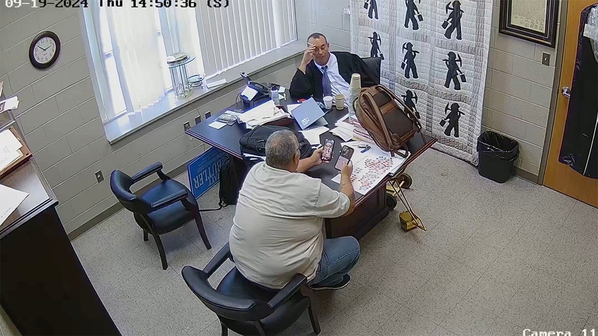 Sheriff Mickey Stines and Judge Kevin Mullins exchange cell phones in Mullins' chambers.