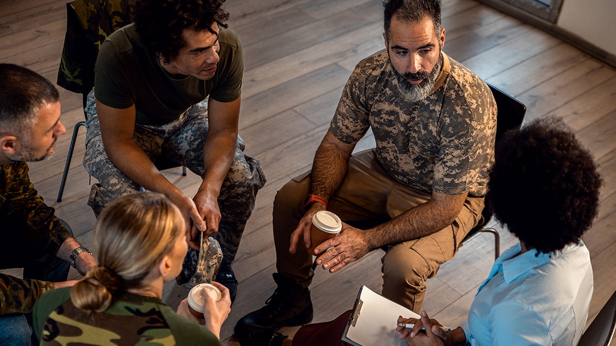 Veterans of diverse backgrounds engaging in conversation during a PTSD support group meeting.