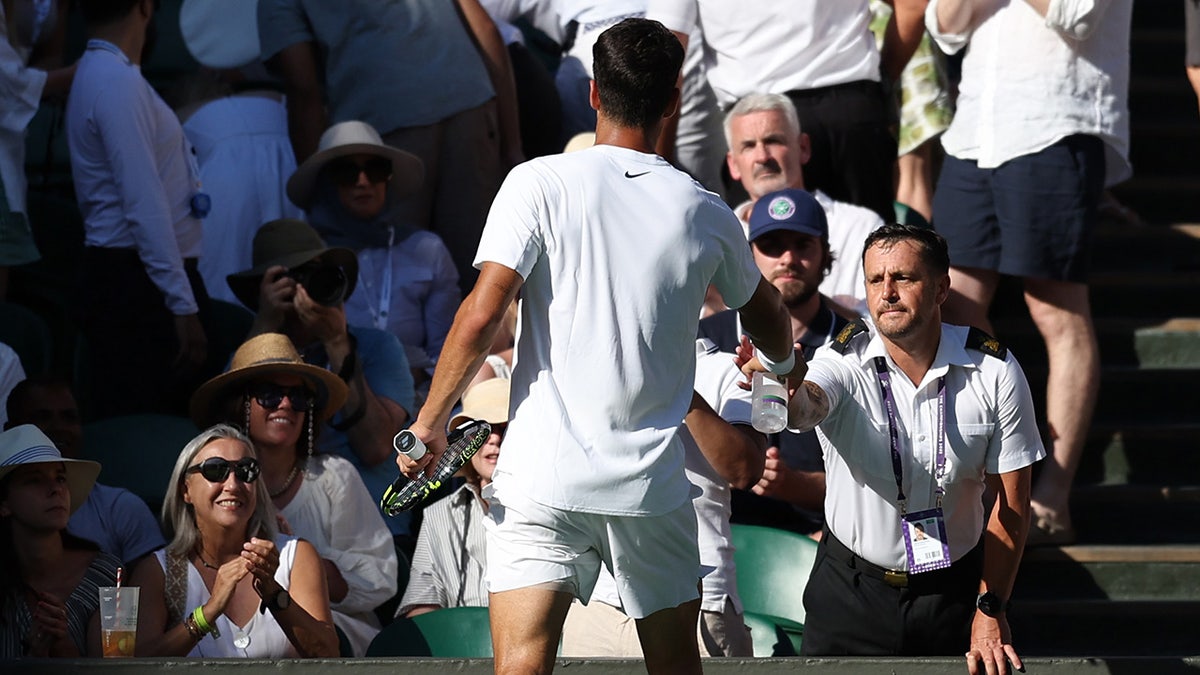 Carlos Alcaraz helps a fan
