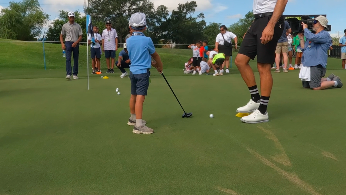 Children practice their golf swing with pros from the HyFlyer GC.Â