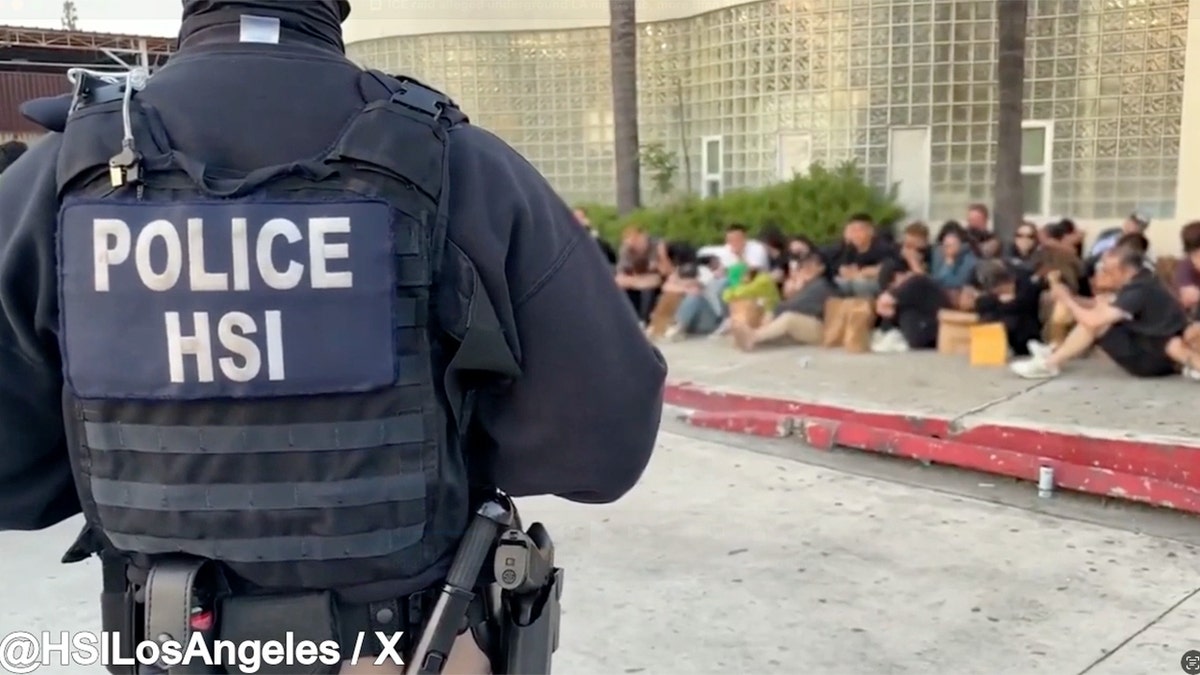 Dozens of Taiwanese and Chinese nationals sit on a sidewalk