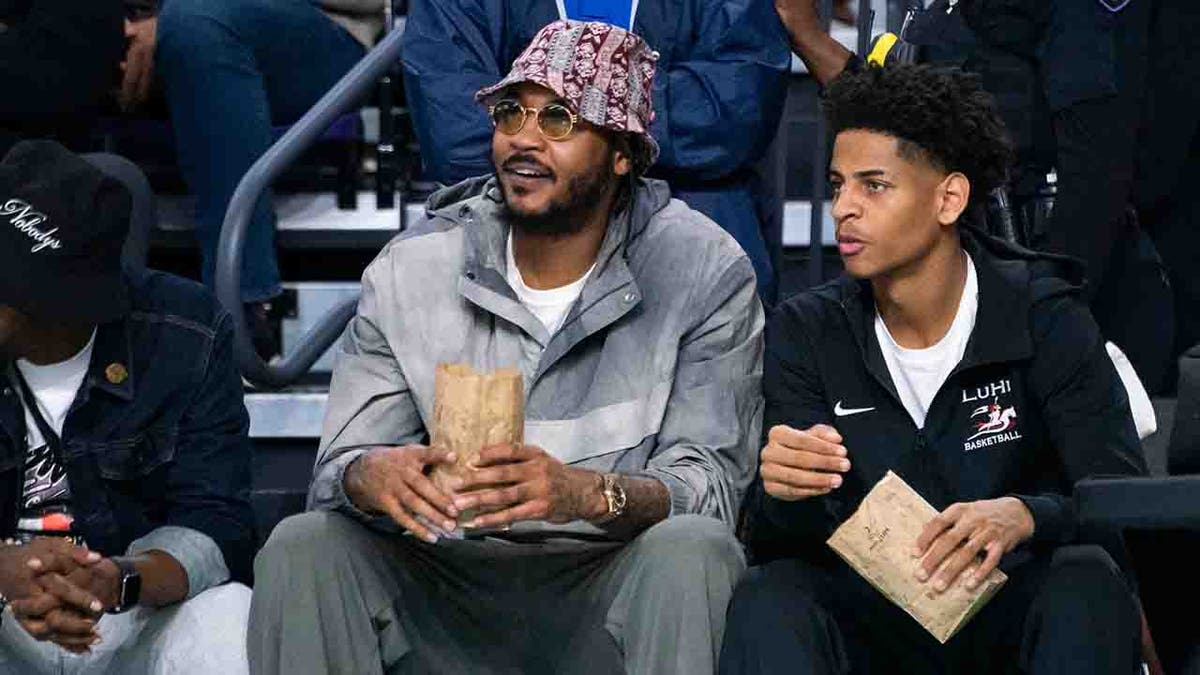 Kiyan and Carmelo Anthony watch a basketball game courtside