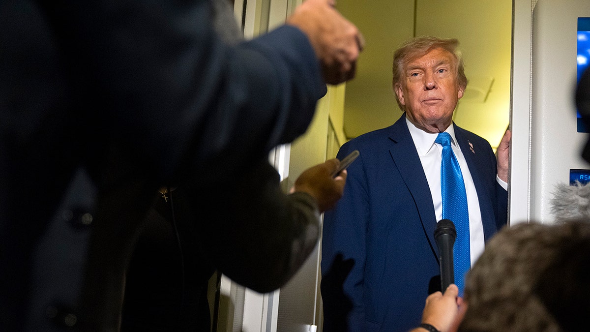 Trump listens to reporters aboard Air Force One