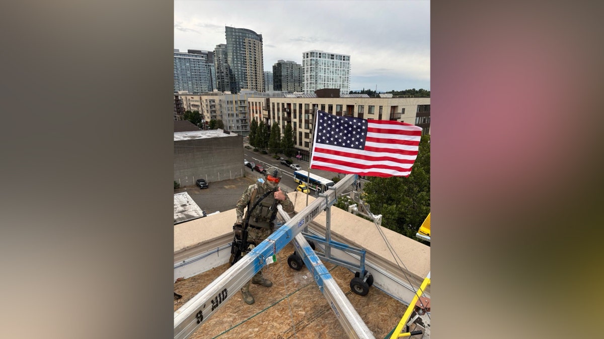 Law enforcement poses next to an American flag erected at the Portland ICE facility.