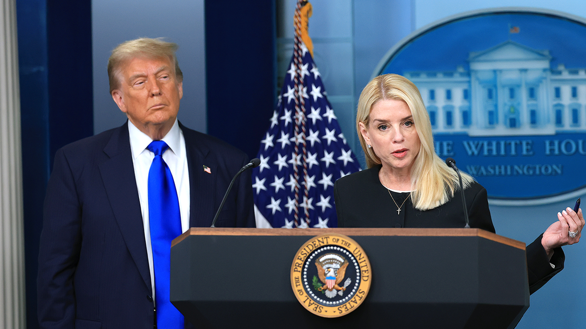 Donald Trump looks at Pam Bondi while she speaks at a podium