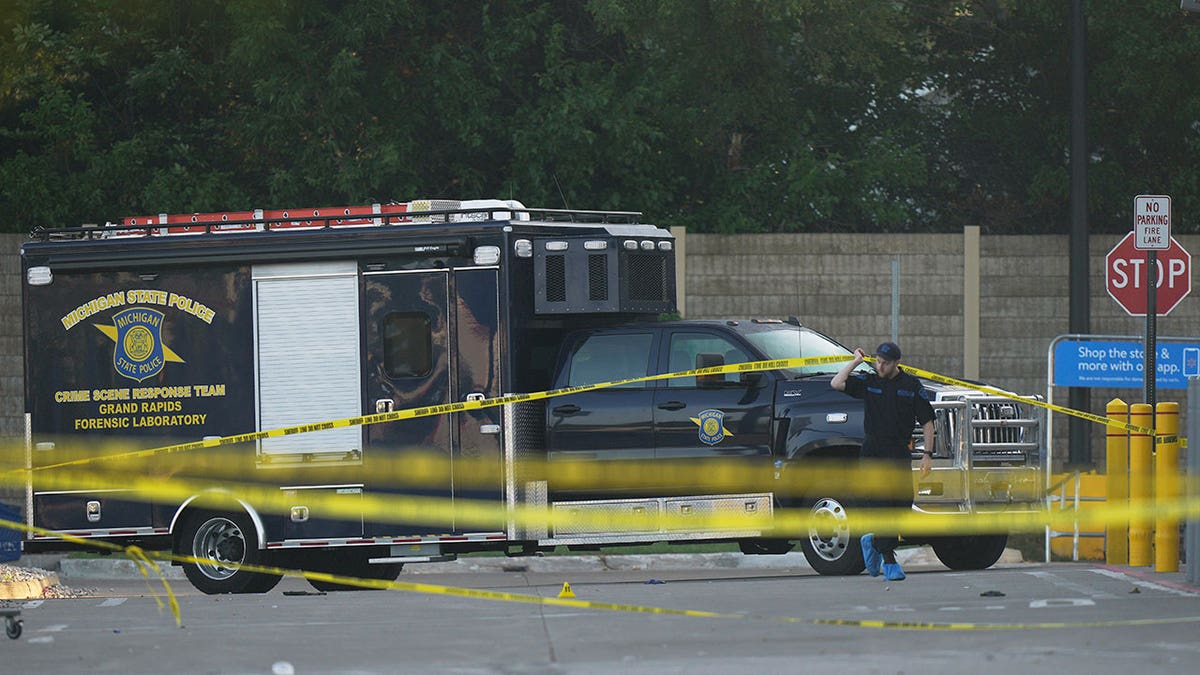 Law enforcement officer walking near state police vehicle and crime tape