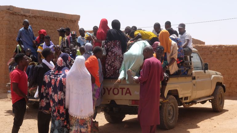 Migrant travellers get into the back of a pickup truck, preparing to head out to the desert