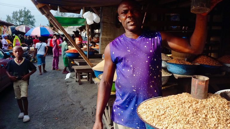 A salesman in Lagos shows the tin he uses to measure seeds.