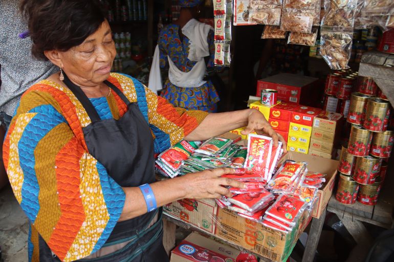 Shopkeeper Agatha Okonkwo shows her tomato paste products.