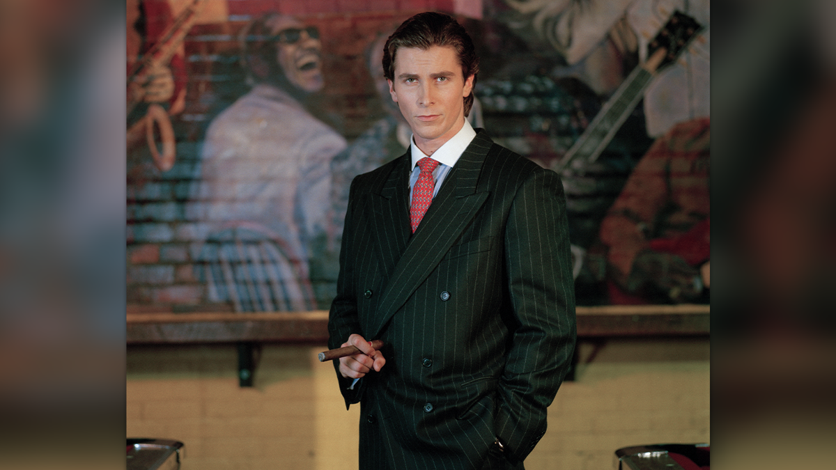 christian bale wearing a pinstriped suit and holding a cigar as patrick batemen on set of 'American Psycho'