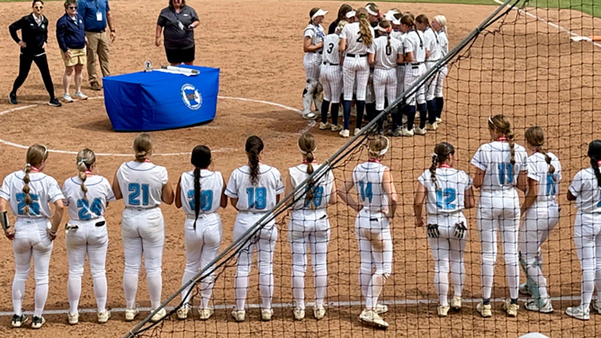 The Champlin Park High School softball team, which was led by a trans pitcher, celebrates winning a Minnesota state championship as members of the defeated Bloomington Jefferson High team look on.