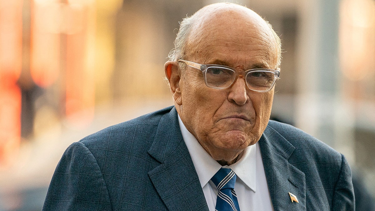 Former New York City Mayor Rudy Giuliani wearing glasses, looking serious