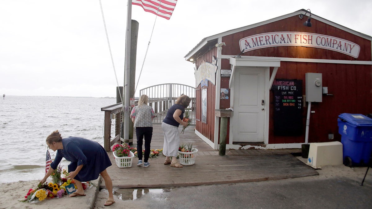 People place flowers in front of the American Fish Company