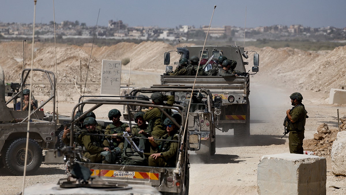Israeli soldiers ride on vehicles into Gaza Strip