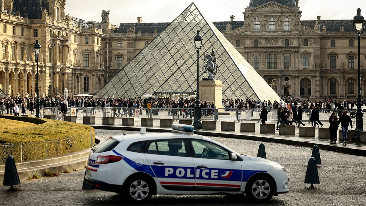 Police car parked outside Louvre Museum.