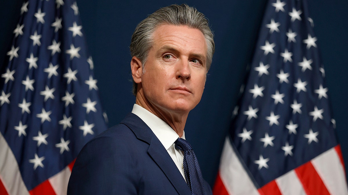 California Gov. Gavin Newsom with two American flags in the background.