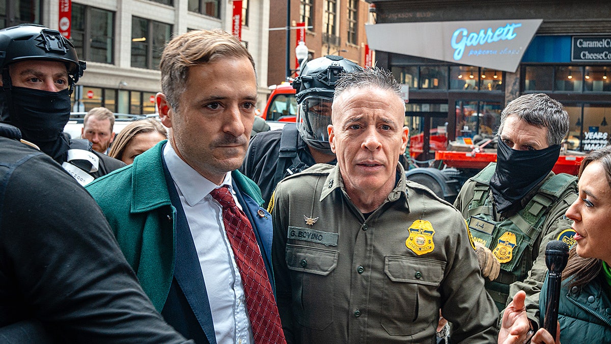 U.S. Border Patrol Commander Gregory Bovino pushes through reporters and protesters while entering the Dirksen Federal Building in Chicago.