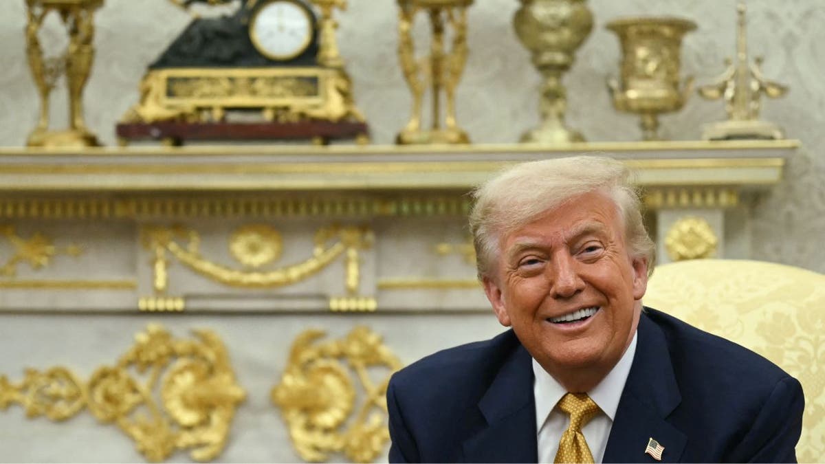 President Donald Trump smiles in the Oval Office
