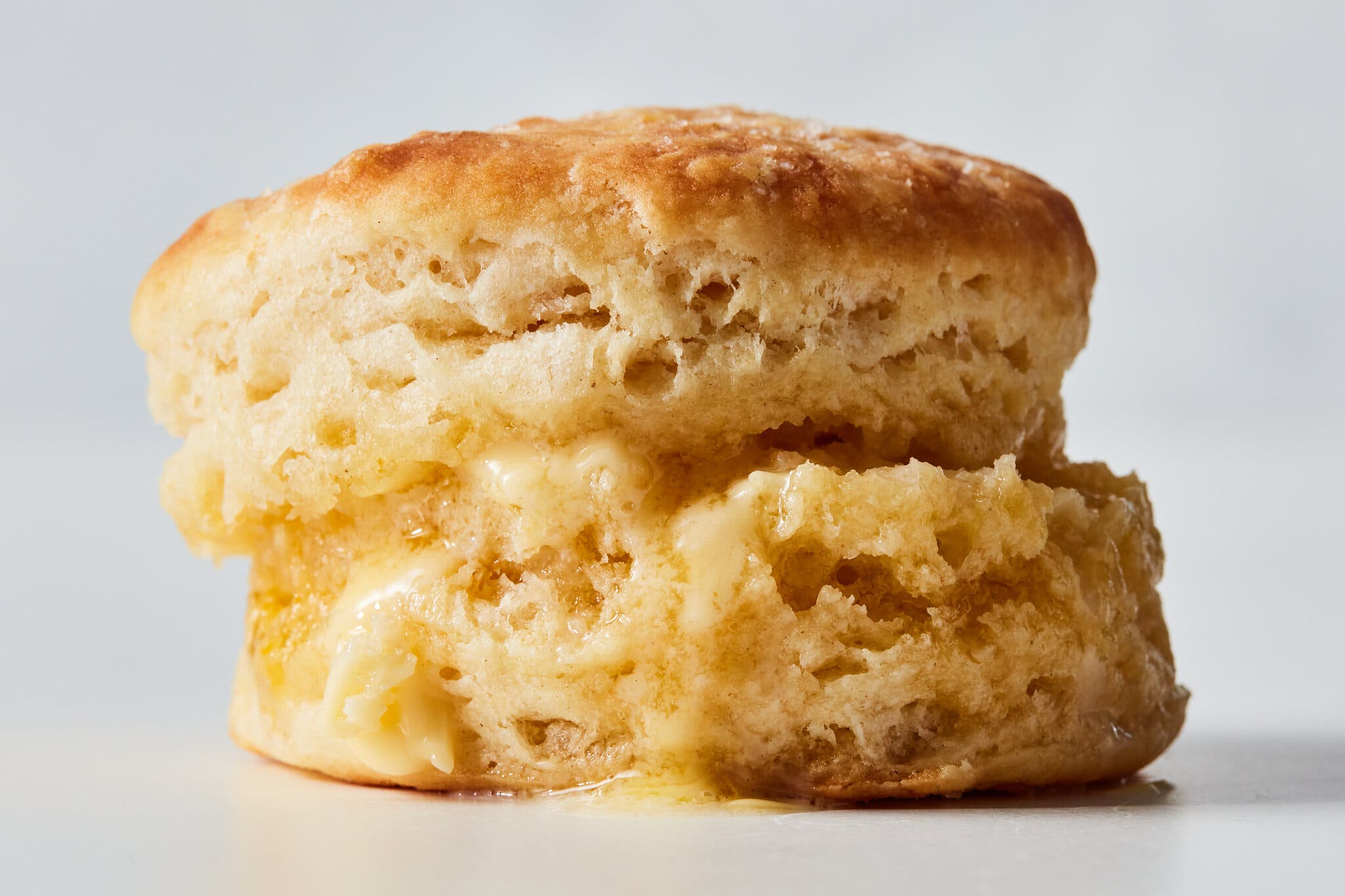A close side image of a single biscuit dripping with melted butter.