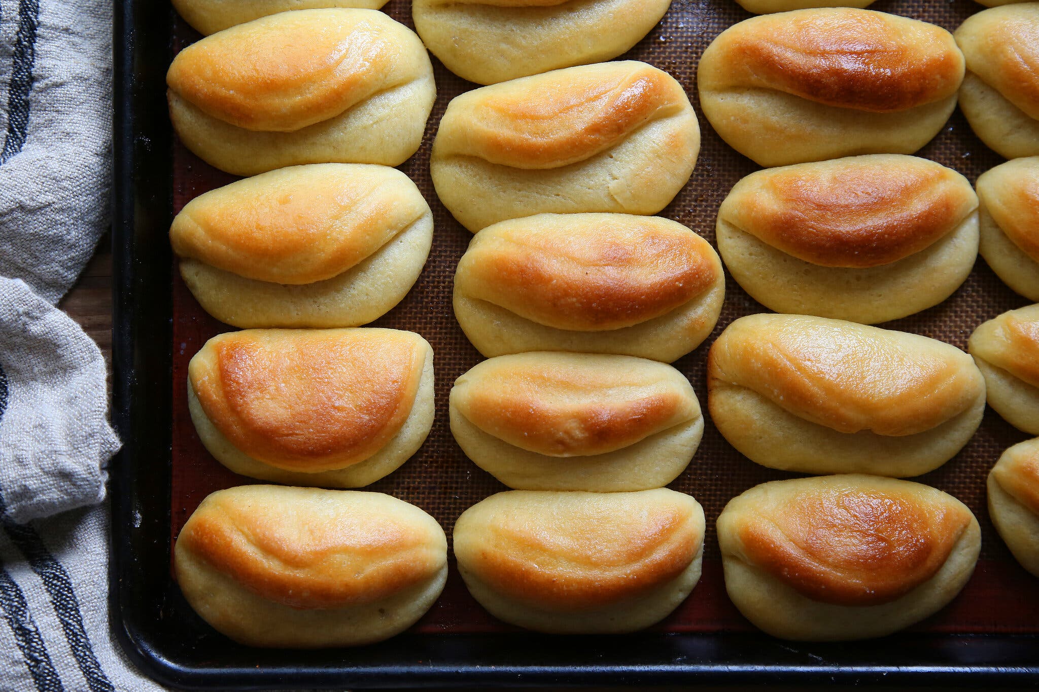 A dozen golden-brown rolls sitting on a baking sheet.