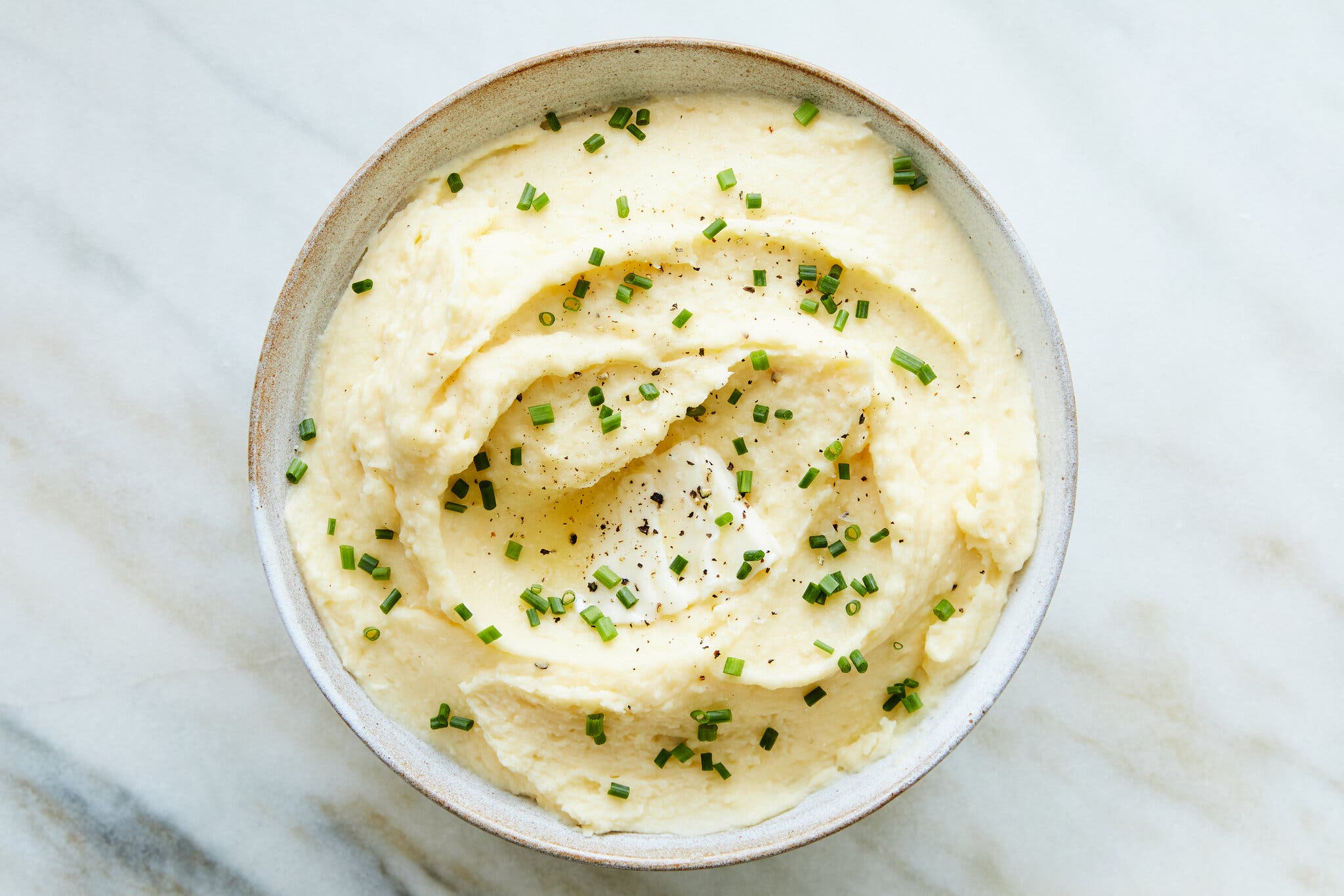 A small bowl of mashed potatoes finished with chives shot from overhead.