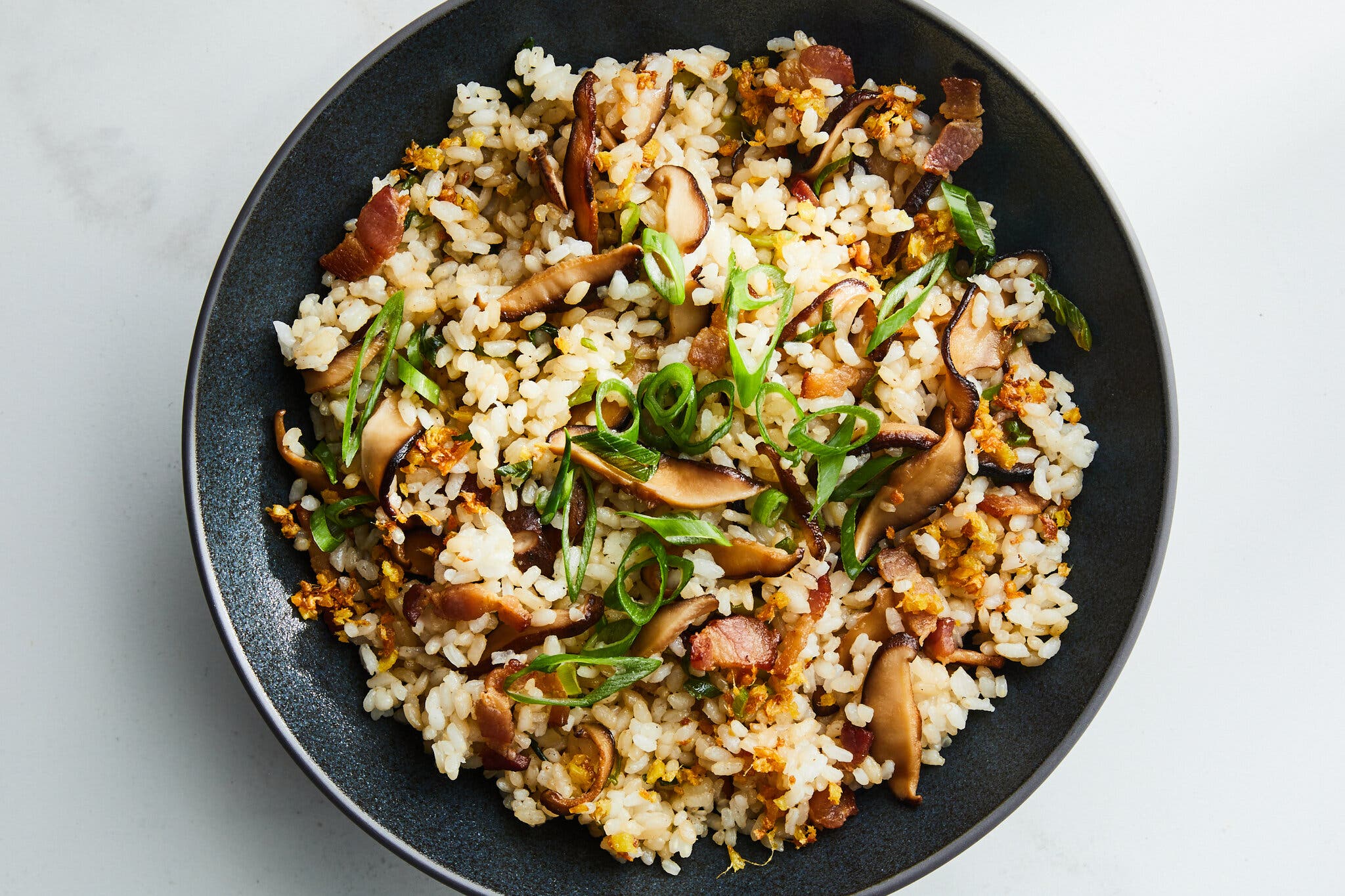 An overhead image of mushroom-studded rice topped with sliced scallions.