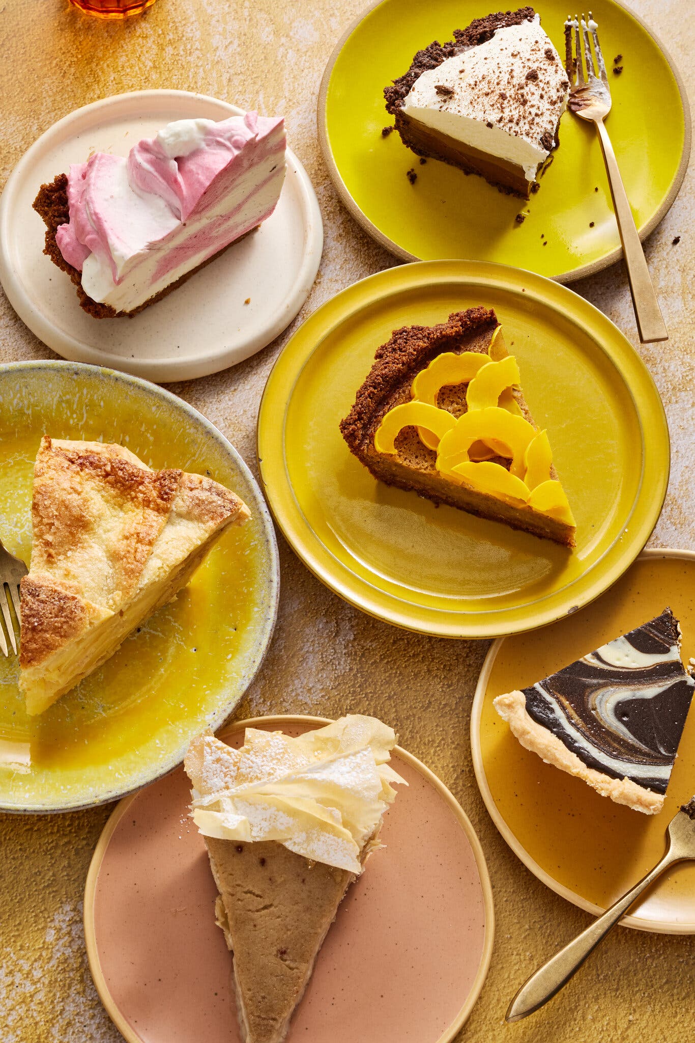 An image of a bunch of slices of pie on brightly colored plates.