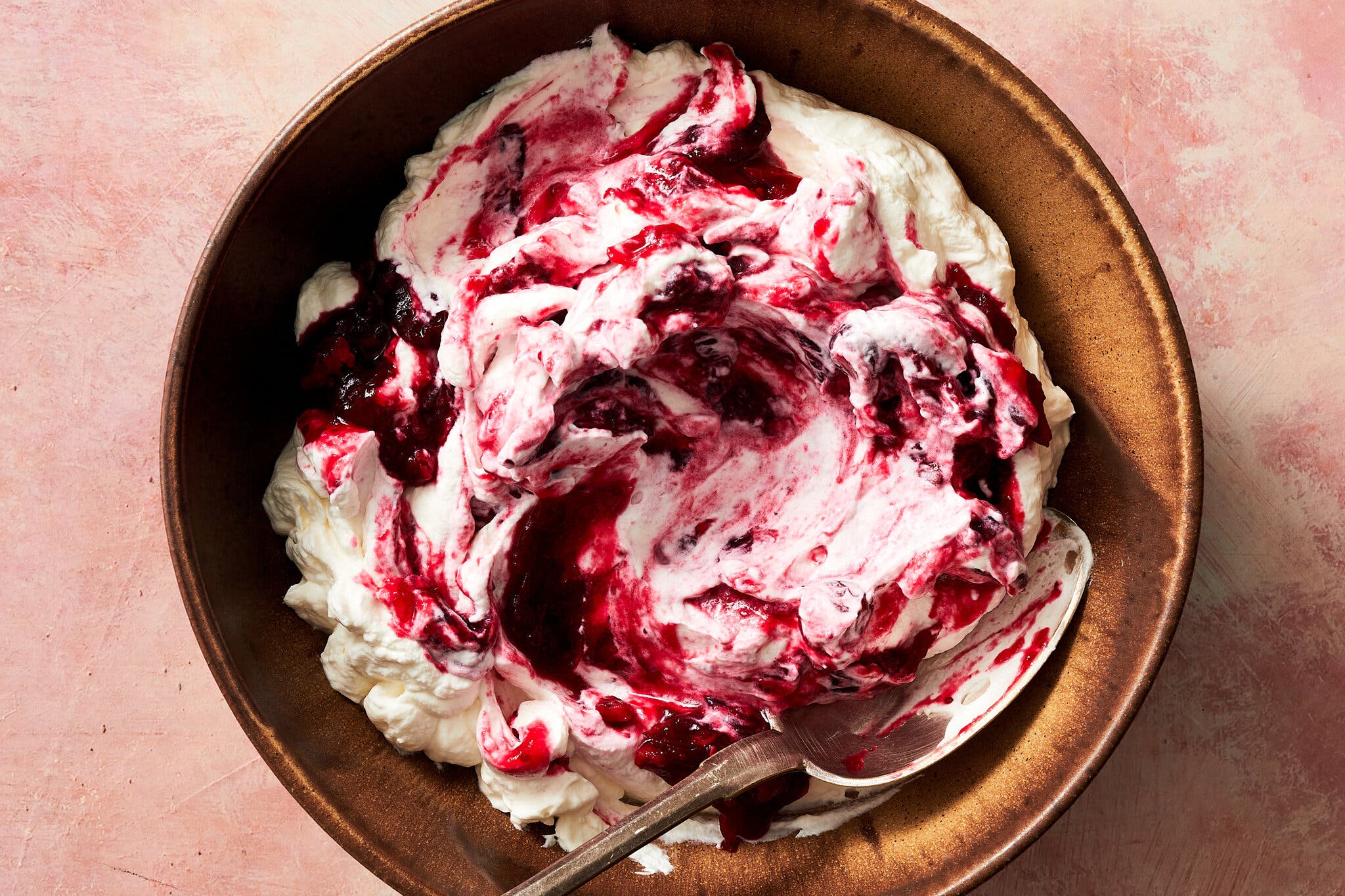 An overhead image of a bowl of cranberry sauce swirled into whipped cream with yogurt.