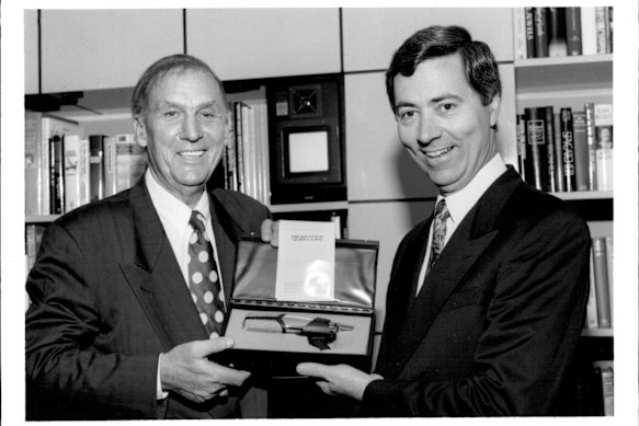 John Laws (left) gets the ultimate gift - his own gold microphone - from 2UE’s John Conde in March 1993.