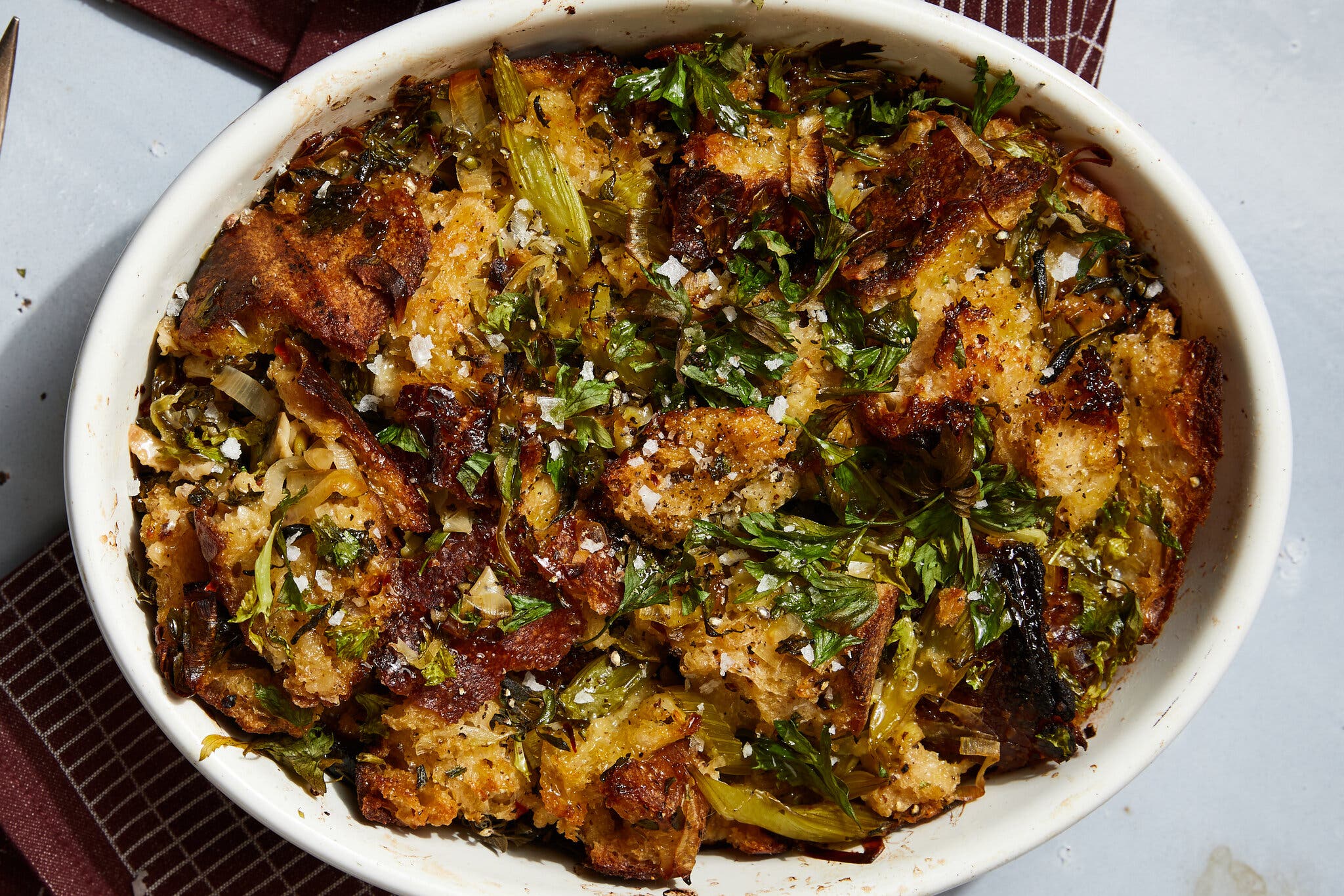 A baking dish of stuffing topped with leeks and herbs.